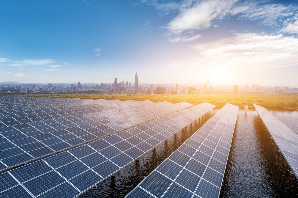 Expansive,Solar,Panel,Field,Overlooking,A,Modern,City,At,Sunset